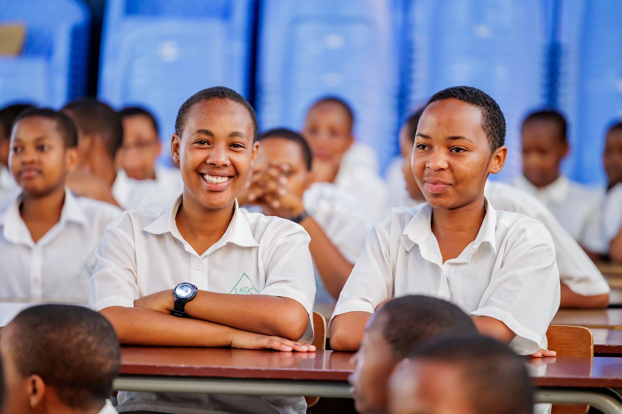 A row of smiling students at their desks in the Great Hall