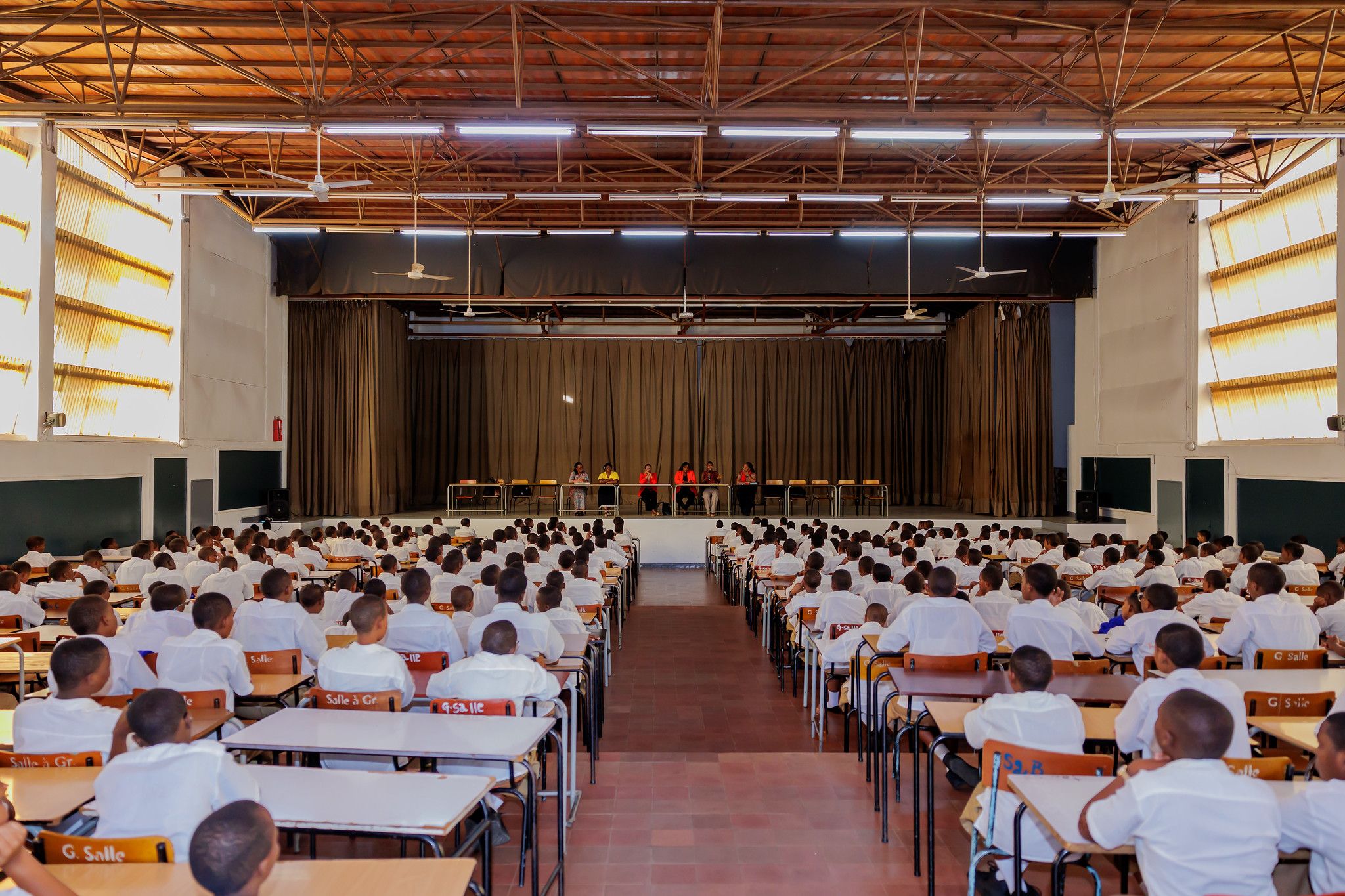The Great Hall from the back: rows of students at desks facing a panel of speakers on stage