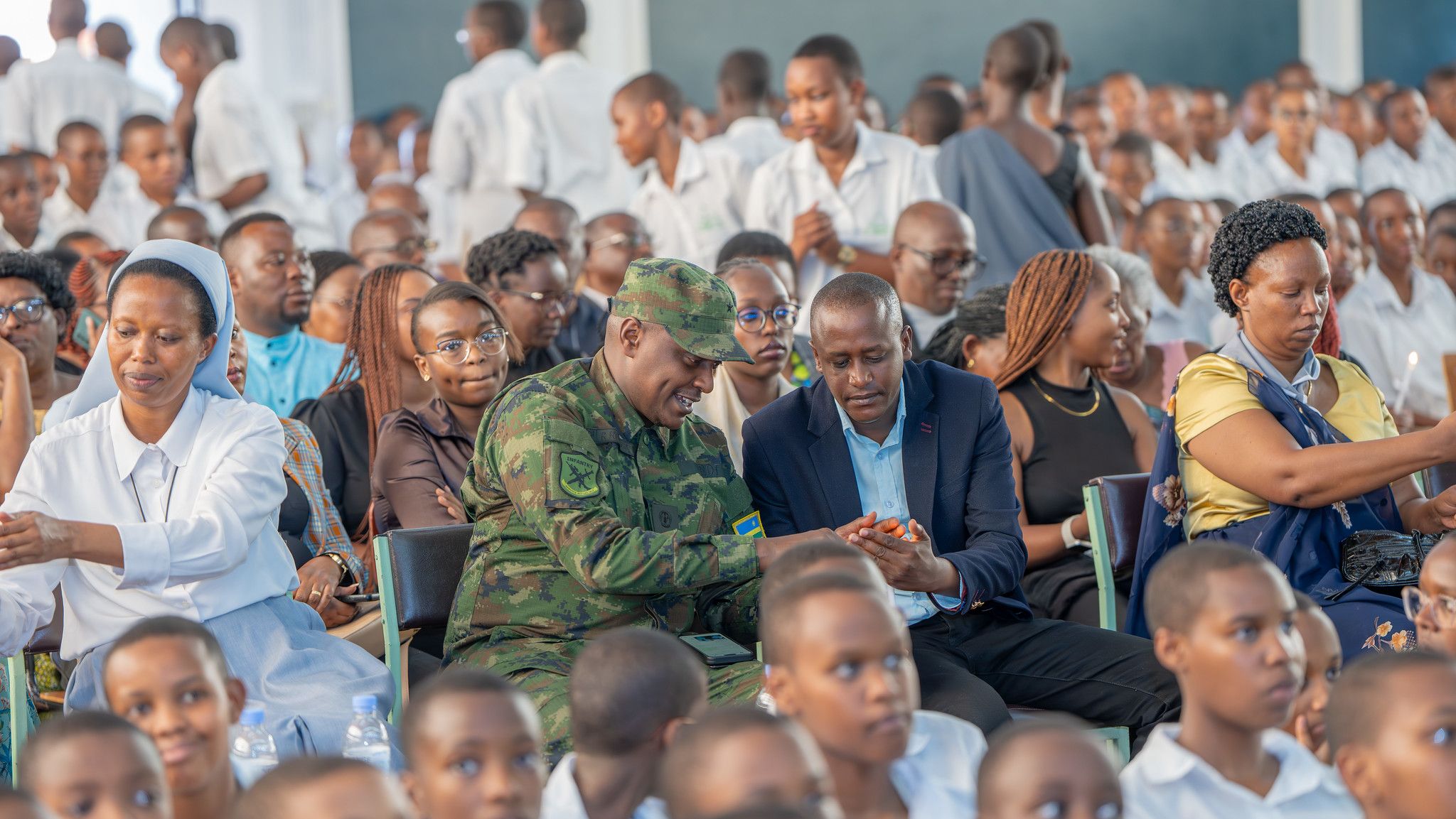 A Sister, staff, parents and guests seated among students at the commemoration